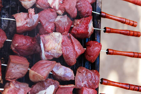 fresh raw turkey fillet steak red meat brisket on skewers barbecue brazier grid full burned charcoalの写真素材