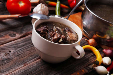 home style beef meat soup vintage country wood table asparagus pepper bell spices bread garlic cutlery eggplantの写真素材