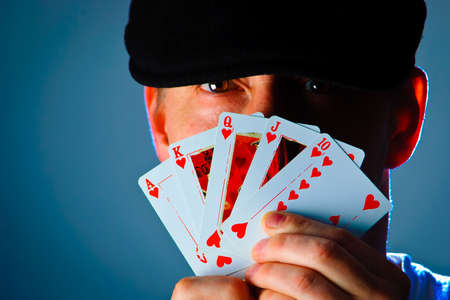 man playing poker with royal flush in front of his face.