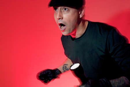 sneeky burglar in black and white with a flashglight caught red handedの写真素材