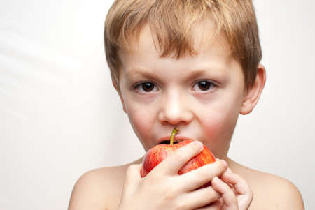 young child holding an apple on a white backgroundの写真素材