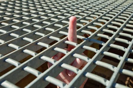 A defiant man flips the middle from behind is cageの写真素材