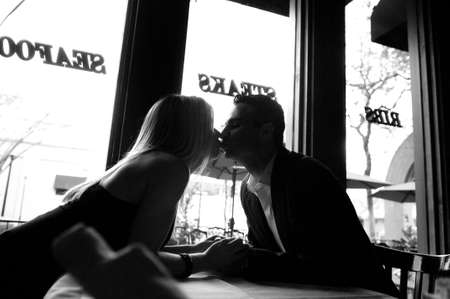 Young couple kissing over table in restaurantの写真素材