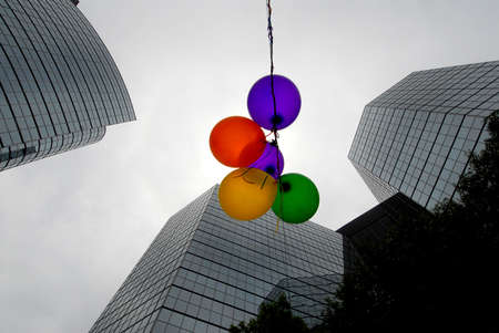 Colored balloons against grey sky and buildingsの写真素材