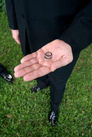Close up view of a groom holding wedding rings in handの写真素材