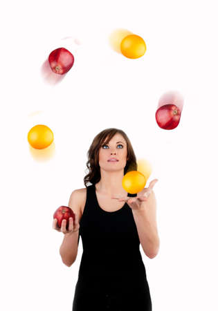 Beautiful woman juggling apples and oranges in motion a white backgroundの写真素材
