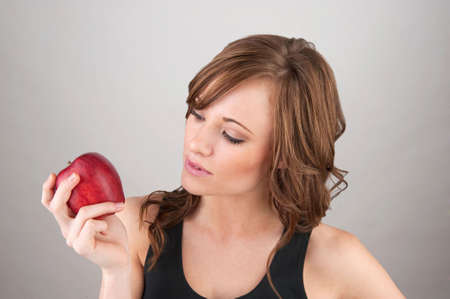 Image of a beautiful gilr holding an apple and examining itの写真素材