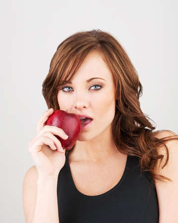 Image of a beautiful girl biting into a red appleの写真素材