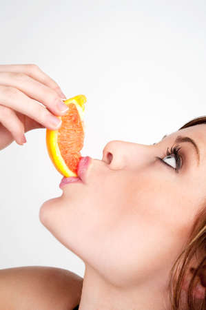 Image of a beautiful girl biting into a slice of grapefruitの写真素材