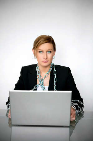Image of a beautiful young businesswoman chained to laptop onneutral backgroundの写真素材