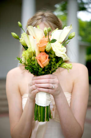 Image of a bride holding her bouquet over her faceの写真素材