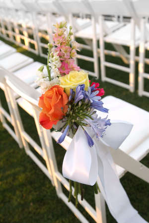 Image of a floral bouquet on a row of white chairsの写真素材