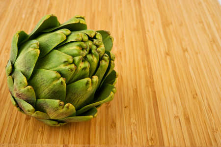 Image of an artichoke on wooden cutting boardの写真素材