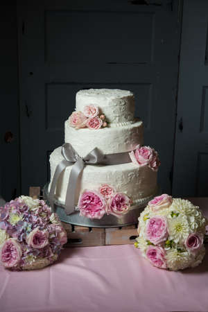 Wedding cake with gray ribbon and pink floral decorの写真素材