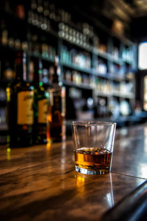 Image of a glass of whiskey on a bar with blurred backgroundの写真素材