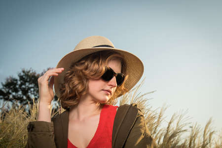 Carefree young woman in a hat with evening sunの写真素材