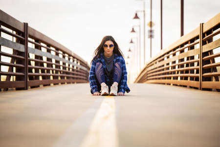 Image of a girl sitting on a yellow line on a bridgeの写真素材