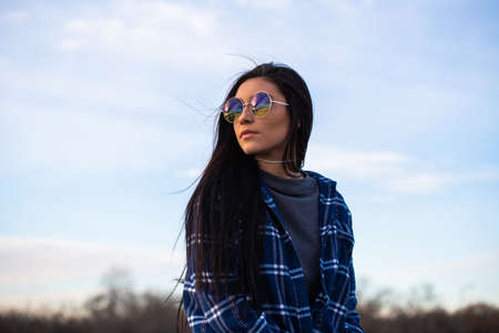 Image of a brunette girl looking over her shoulder wearing blue sunglassesの写真素材