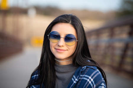 Image of a brunette girl wearing blue sunglasses and smiling at the cameraの写真素材