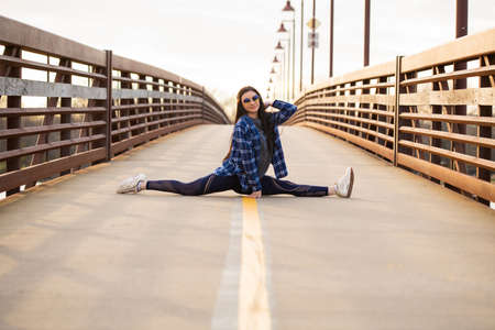 Image of a brunette girl doing the splits on a bridge and smilingの写真素材