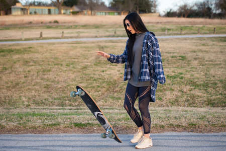 Image of brunette girl flipping up her skateboard in actionの写真素材