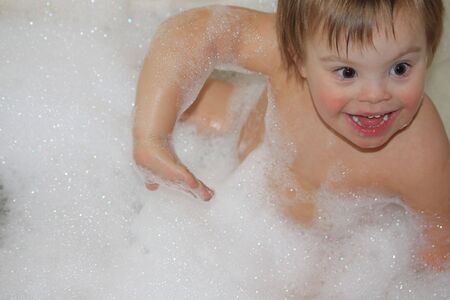 Special needs child playing in bathtub