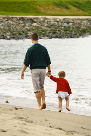 Big brother walking little brother on beachの写真素材