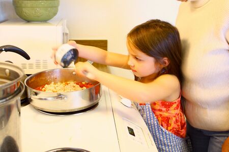 Little girl helping Mom cookの写真素材