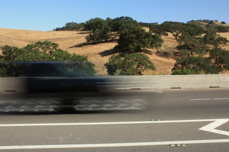 Blurred black vehicle passing by on highway