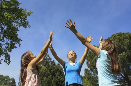 Three girls with hands held up to the skyの写真素材