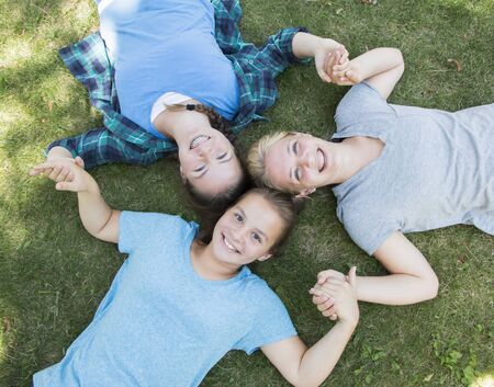 Three Girls Lying on The Green Grassの写真素材