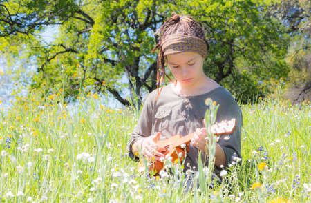 Cute Young Girl With Ukulele in Green Grassy Fieldの写真素材