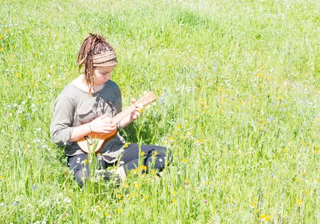 Cute Young Girl With Ukulele in Green Grassy Fieldの写真素材