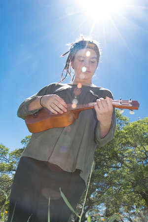 Cute Young Girl With Ukulele Under Sunlight Skyの写真素材