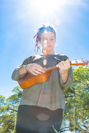 Cute Young Girl With Ukulele Under Sunlight Skyの写真素材
