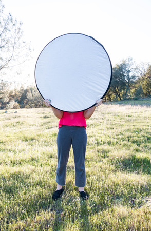 Young Girl Holding up Light Diffuser With Both Handsの写真素材