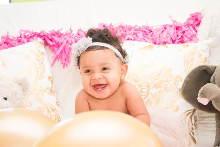 Cute Baby Girl Sitting With Pillows and Balloonsの写真素材