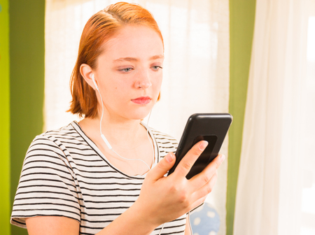 Beautiful Young Redhead Girl Looking at Cellphoneの写真素材