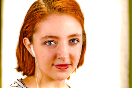 Young Redhead Girl With Headphones Looking at Cameraの写真素材
