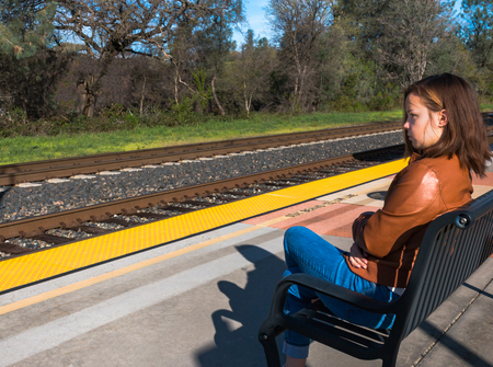 Cute Young Girl Sitting Near Train Railsの写真素材