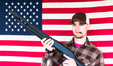 Young Man With Shotgun on American Flag Backgroundの写真素材