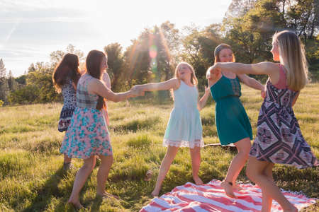 Young Girls Dancing in Grassy Field and Enjoying the Sunlight Overheadの写真素材