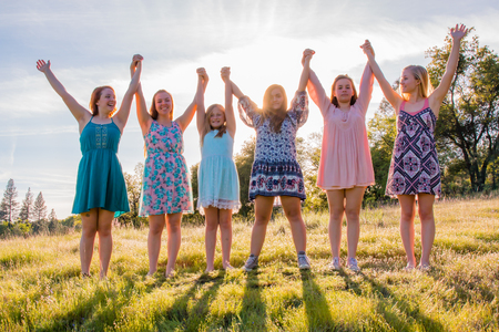 Group of Girls Standing With Arms Raised and Sunlight Overheadの写真素材