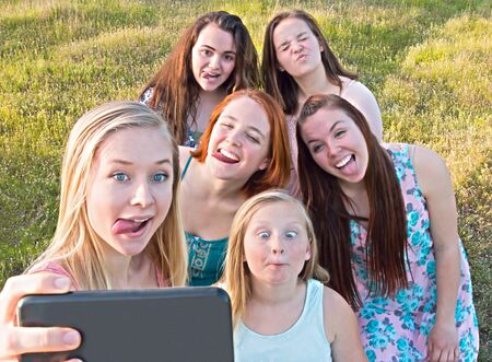 Group of Cute Young Girls  Taking a Selfie with Green Grass in the Backgroundの写真素材
