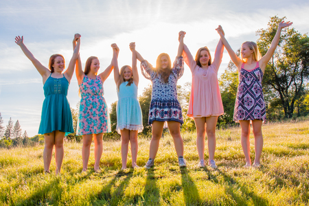 Group of Girls Standing With Arms Raised and Sunlight Overheadの写真素材