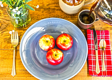 Place Setting With Red Apples, Flowers and Crockery on Wooden Table With Knots and Brewed Coffee Poured in Cupの写真素材