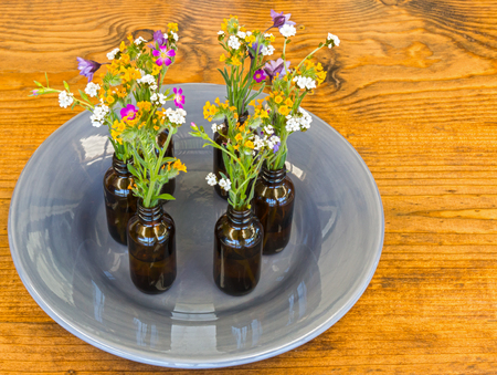 Gray Plate With Small Vases With Flowers Sitting on Wooden Tableの写真素材