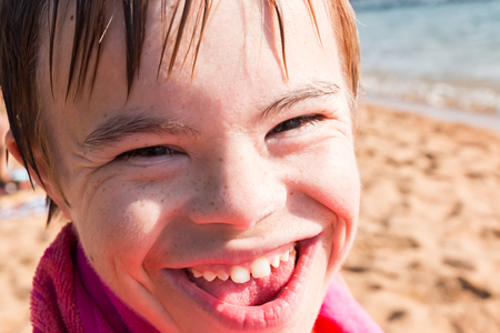 Beautiful Boy With Downs Syndrome Sitting at the Beachの写真素材