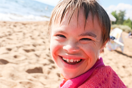 Beautiful Boy With Downs Syndrome Sitting at the Beachの写真素材