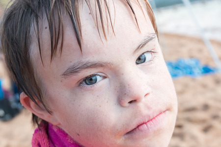 Beautiful Boy With Downs Syndrome Sitting at the Beachの写真素材